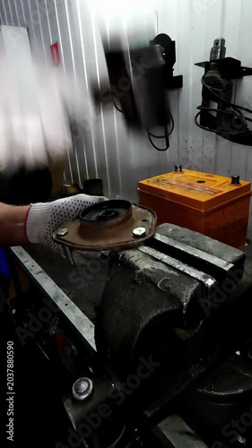  A gloved hand strikes a car part with a hammer