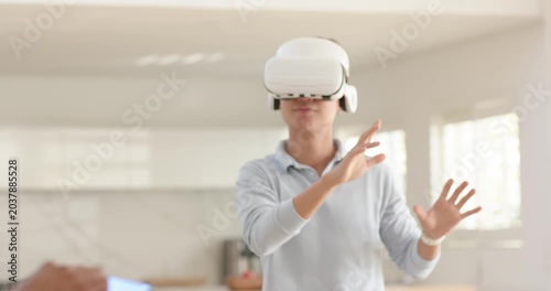 Male friends seeing phone alert, Asian man gesturing in VR, removing headset, testing robot at home