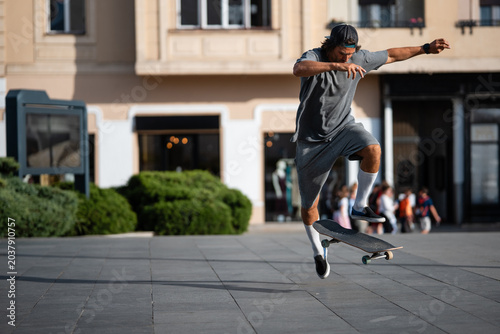Bild auf Leinwand Skateboarder performing ollie trick in city square