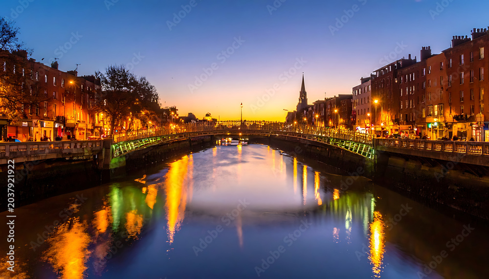 Fototapeta premium City canal at dusk reflecting glowing lights from buildings and bridges, serene evening atmosphere, Dublin Ireland