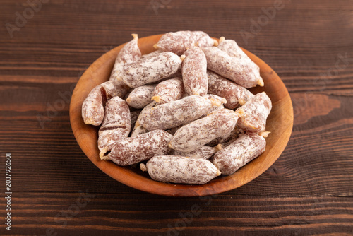 Small smoked Chicken sausages in wooden bowl on brown wooden. side view, close up