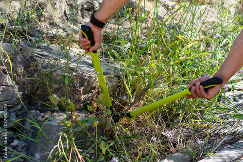 POV hands using garden shears cutting grass outdoors