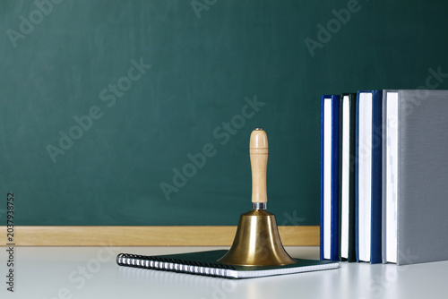 Εκτύπωση καμβά School golden bell, copybook and notebooks on white table near green chalkboard