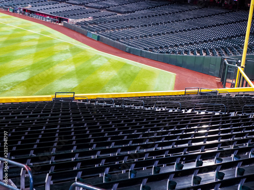 Fotografie Empty green bleacher seats in left field of a baseball stadium, groomed green gr