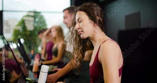 Group of friends workout together at fitness center while using machines and having fun during exercises in the morning