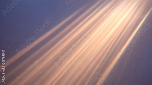 Golden sun rays illuminating particles and dust in a dark room creating an abstract and peaceful background with light beams
