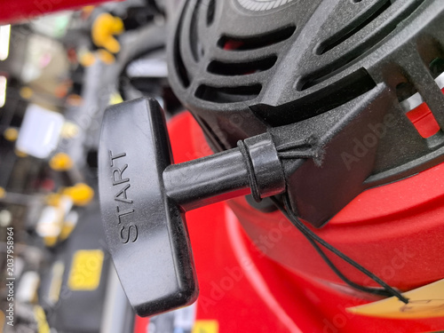 Foto A bright red lawnmower with a shiny pull-start mechanism sits ready for action