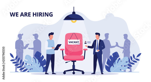 Hiring manager and applicant standing near a vacant office chair with a sign in a busy company office interior.