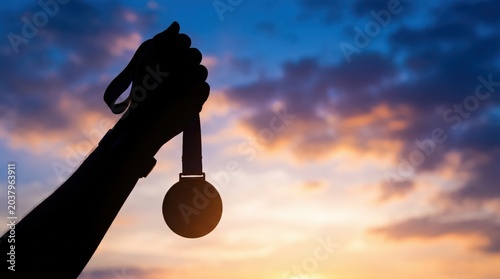 Celebrating Achievement at Sunset: A Symbol of Perseverance and Success Depicted by a Medal