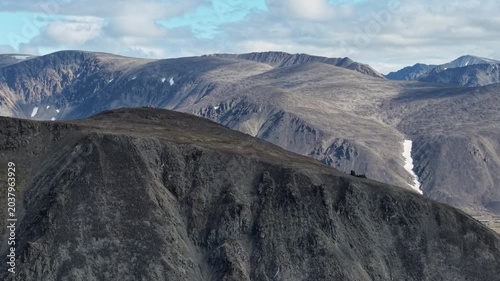 Daylight view of rocky mountain massif in Russia, Chukotka, Lavrentiya. Dramatic push in toward snow gullies and dark ridges for an epic panorama. UAV aerial footage for travel editorial