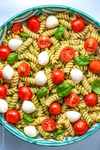 Summer Italian salad with fusilli pasta, mini mozzarella, cherry tomatoes, pesto sauce, and basil. Summer Italian menu  