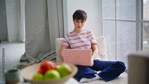 Remote worker using laptop sitting floor modern home. Woman reviewing emails