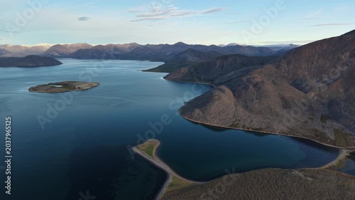 Aerial shot of coast near Provideniya, Penkigney Bay in Chukotka . Drone pan reveals bays, islands and mountain ridges in golden light. Arctic landscape for travel, adventure use