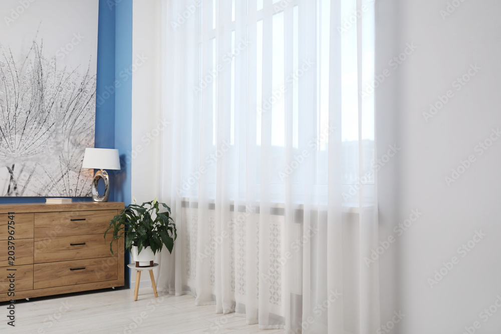 Fototapeta premium Houseplant near window with stylish curtains in room. Interior design