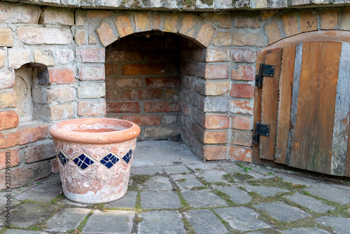 Rustic weathered planter with peeling surface in front of a brick wall