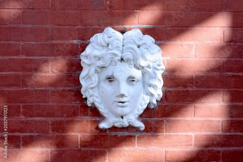 Bild auf Leinwand Sculpture décorative de visage blanc sur mur en briques rouges