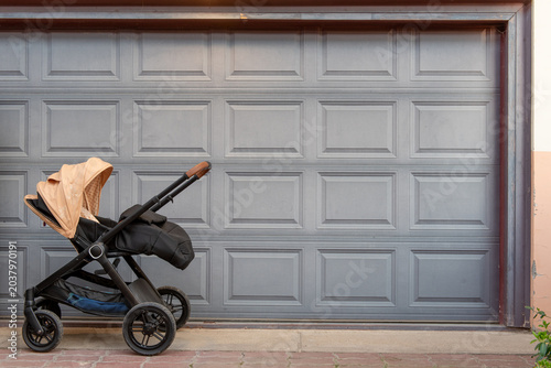 beige-black stroller in front of garage door.