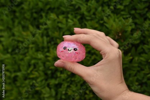 Tableau sur toile Horizontal photo of a hand holding a trendy dumpling squishy toy against a green natural background