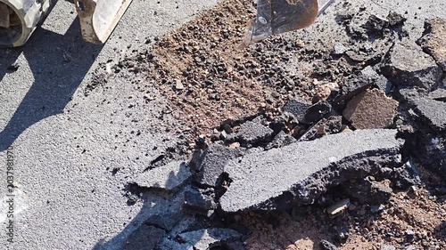 Excavator bucket breaking and crushing concrete slab at outdoor demolition site
