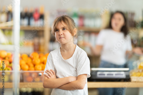 Tablou pe pânză Angry child is standing in grocery store, capricious and sulky silence