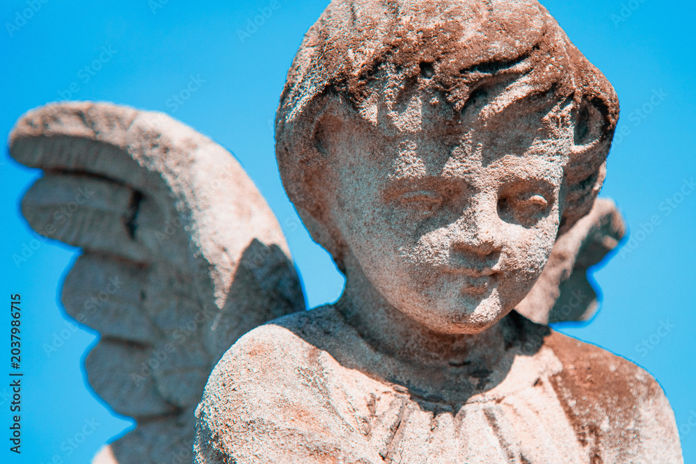 Obraz premium Guardian angel child statue against bright blue sky.