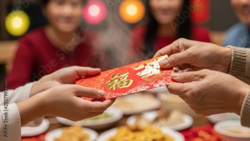 Close-up of hands giving a red envelope during a Chinese New Year celebration.