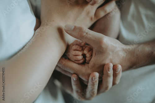 Fotografie Gros plan sur les petits pieds d'un bébé enveloppés avec amour par les mains de