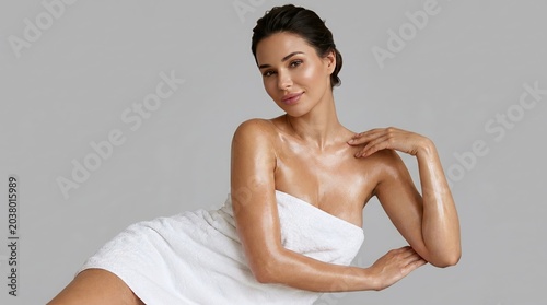 Stunning woman with radiant, healthy skin wrapped in a soft white towel, exuding a beautiful glow after a luxurious spa treatment, showcasing natural beauty and well-being