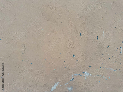 Muted earth-toned wall displaying coarse irregularities and scattered vestiges of obscure dark