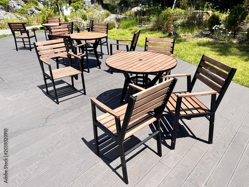 Konstfotografi Empty wooden tables and chairs on an outdoor terrace in a garden park