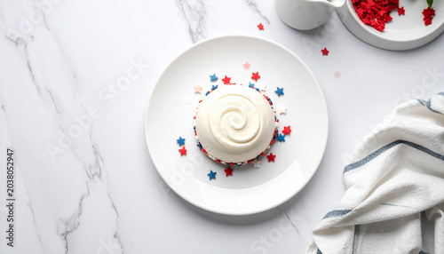 Patriotic Dessert Delight: A creamy white frosted dessert, adorned with red and blue star sprinkles, sits atop a white plate, ready for a festive celebration.