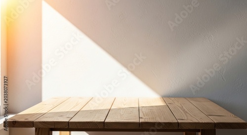A wooden table sits in a room with a beam of sunlight shining on it