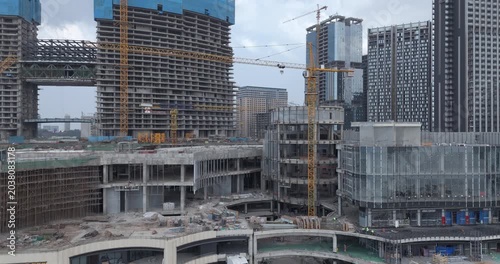 aerial view of a sprawling urban construction site in Sihanoukville features multiple high-rise buildings in various stages of development, dominated by towering cranes and concrete frameworks