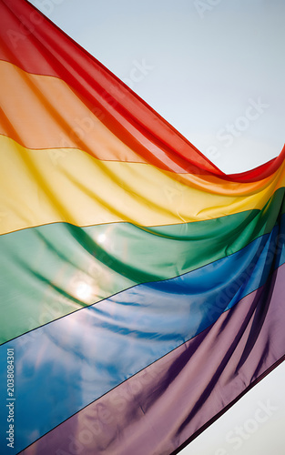 Vibrant rainbow flag waving in the wind with colorful stripes and sunlight shining through fabric