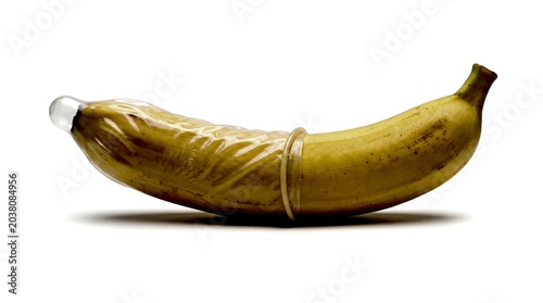 Banana with a rolled latex condom isolated on a white background for safe sex education, contraception awareness, reproductive health, and medical advertising.