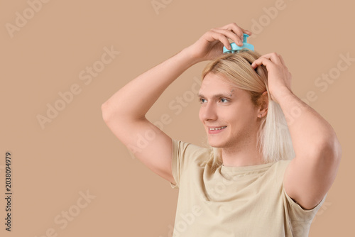 Young blonde man using hair...