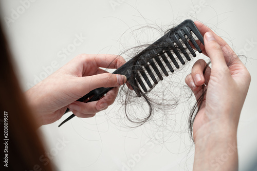Asian woman have problem with long hair loss attach to comb brush.