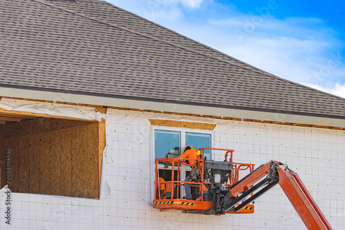 Foto A wide horizontal view of construction workers in an orange boom lift basket ins
