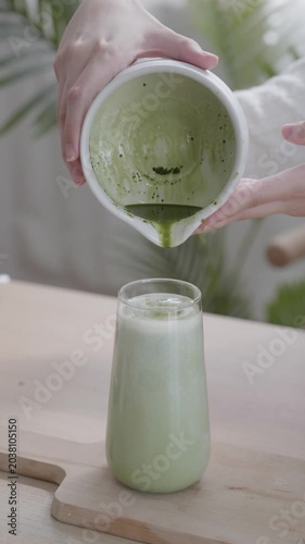 Pouring Matcha Green Tea Concentrate into a Glass of Milky Latte