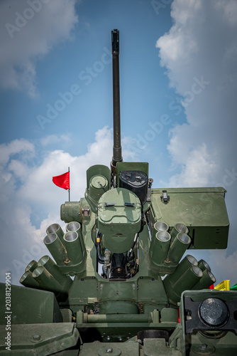 Foto Low angle view of a modern military remote weapon station (RWS) equipped with a heavy machine gun, optical sensors, and smoke grenade launchers under a blue sky