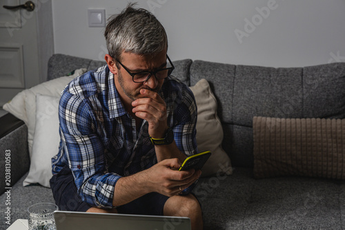 Exhausted freelancer checking smartphone at home