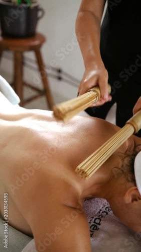 Woman Receiving Relaxing Bamboo Broom Back Massage in Spa