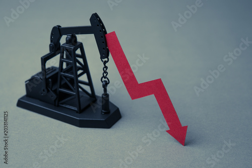 Foto Crude oil pumpjack with red falling prices chart on grey background copy space