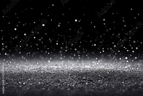 Abstract black and silver background with scattered glittering particles in motion.