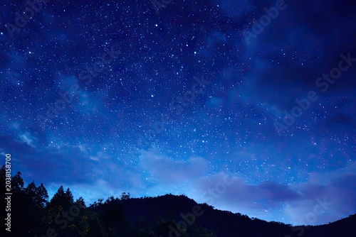 Deep blue night sky, stars, and silhouetted hills
