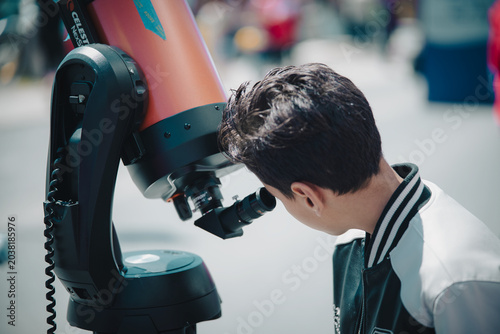 Young person observing through telescope during astronomy event