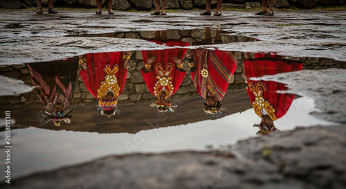 Reflections of traditional figures in a puddle.