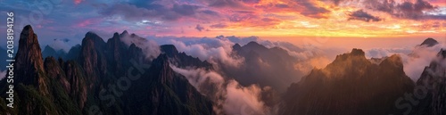 Panoramic view of dramatic mountain peaks at sunset, shrouded in clouds