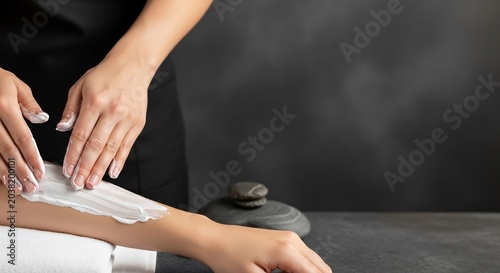 Close-up of a beautician applying wax to a clients arm for hair removal.