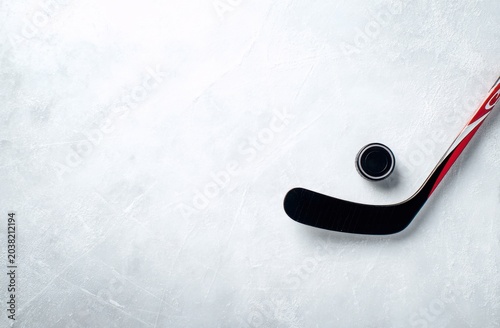Hockey stick and puck on a clean ice rink surface, top view
